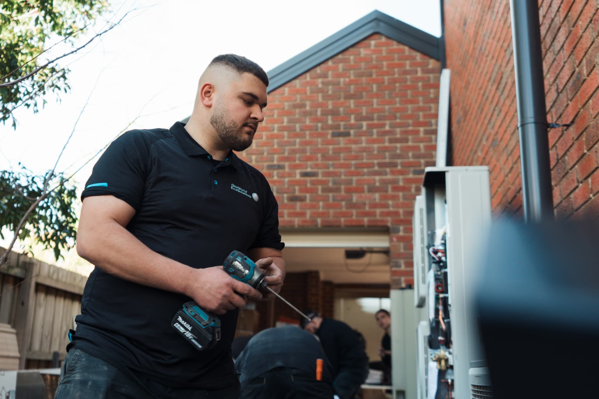 OneWorld EcoSolutions installer working on an outdoor air conditioning unit