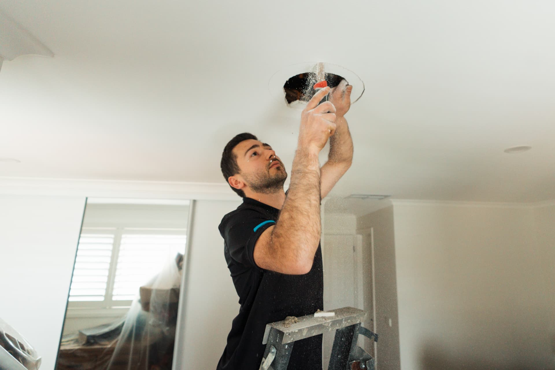 OneWorld EcoSolutions installer preparing a ceiling opening for ducted air conditioning