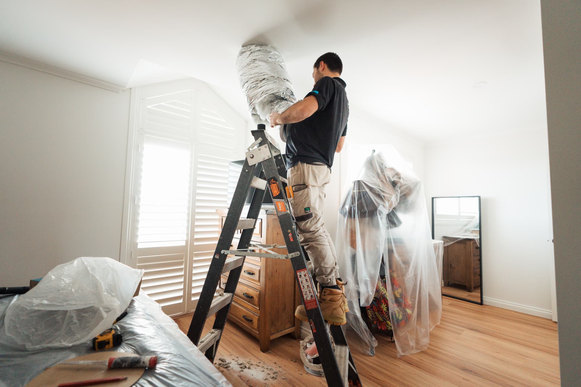 Technician installing ducted air conditioning inside a home